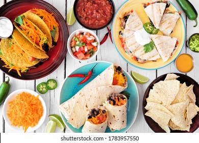 Mexican Food Table Scene, Overhead View On A White Wood Background. Tacos, Burritos, Quesadilla And Nachos.