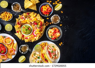 Mexican food, various dishes, shot from the top on a black background with copy space. Nachos, tacos, tequila