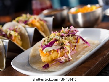 Mexican fried cod fish taco served with lettuce, red onion and sauce - Shutterstock ID 384458443