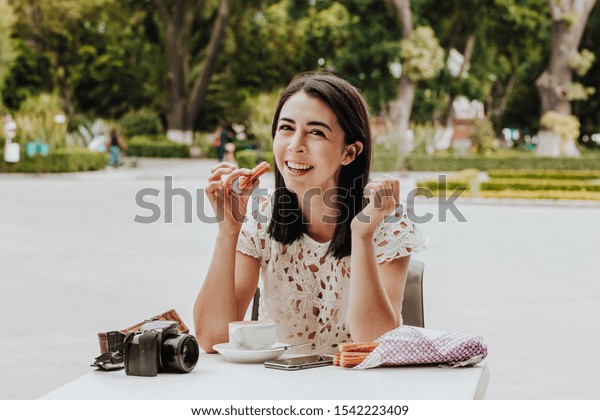 伝統的なチュロスを食べるメキシコの女の子 メキシコの喫茶店でチョコレートを入れた揚げたペストリー ヒスパニック系の女の子 の写真素材 今すぐ編集