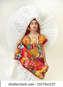 Mexican Girl With A Floral Dress From Oaxaca Mexico, Hidden In A Red Background With Braided Flowers And Gold Necklaces, For Mexican Culture Dance