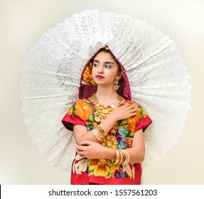 Mexican Girl With A Floral Dress From Oaxaca Mexico, Hidden In A Red Background With Braided Flowers And Gold Necklaces, For Mexican Culture Dance