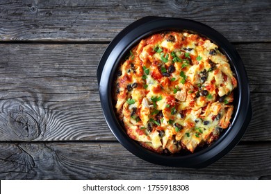 Mexican Gluten-free Tamale Pie Of Cornmeal Crust With Pulled Chicken, Cheddar Cheese, Black Bean Filling Baked On A Black Baking Dish On A Wooden Background, Top View, Copy Space