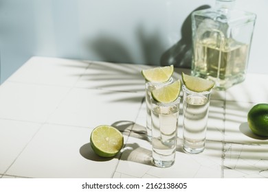 Mexican Gold Tequila with lime and salt on white background with shadows and copyspace.