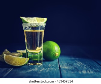 Mexican Gold Tequila with lime and salt on dark table. Toned. Retro style vintage color. Copyspace for text.