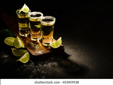 Mexican Gold Tequila with lime and salt on wooden table, selective focus. Copyspace.