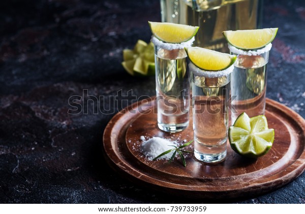 Mexican Gold Tequila with lime and salt on\
black background with\
copyspace.