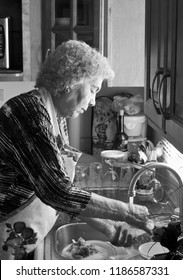 Mexican Grandma Washing Dishes In Black And White Portrait.