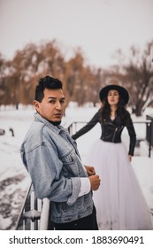 Mexican Hispanic Man In Oversized Denim Jacket And Woman In Hat Leather Biker Jacket Kissing Hugging Laughing Walking.groom Bride Wedding Love Couple In Winter Snow.fashionable Stylish Party Wedding