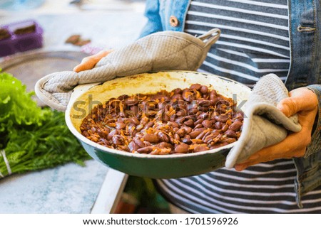 Mexican hot spicy beans in frying pan. Vegan food. Woman hands