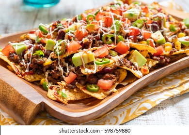 Mexican nacho yellow corn tortilla chips with cheese, meat, avocado guacamole and red hot spicy salsa