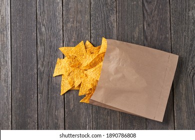 Mexican Nachos Chips Spill Out Of  Large Package On A Rustic Wooden Table. Packaging Of Nachos Chips On A Rustic Wooden Table. Bag Or Packet Mexican Nachos Chips.