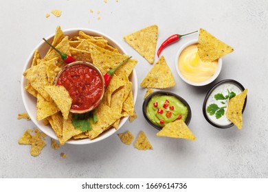 Mexican Nachos Chips With Various Sauces - Guacamole, Salsa, Cheese And Sour Cream. Top View Flat Lay On Stone Table