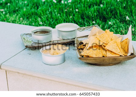 Mexican nachos with three kind sauce served on concrete background in a park. Snack for party, picnic, chips with sauces: cheese and mayonnaise (tartar), copy space. Stock photo © 