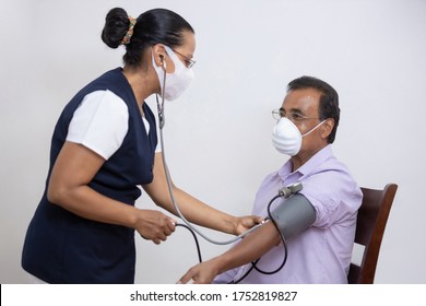 Mexican Nurse Taking Blood Pressure To A Patient At Home