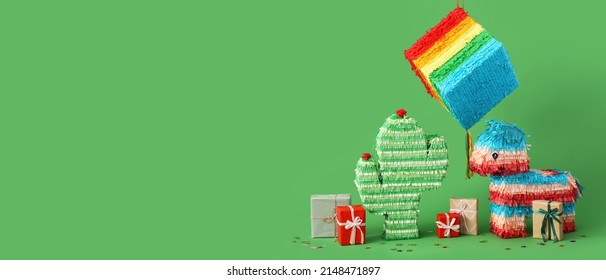 Mexican pinatas with gifts on green background with space for text