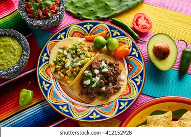 Mexican platillo tacos of barbacoa and vegetarian with sauces and colorful table