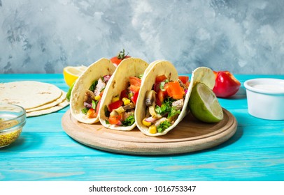 Mexican pork tacos with vegetables on wooden blue rustic background.
