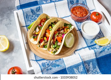 Mexican pork tacos with vegetables on wooden blue rustic background.