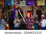 Mexican Posada and family breaking a traditional pinata to celebrate Christmas eve in Mexico Latin America, hispanic people and traditions 