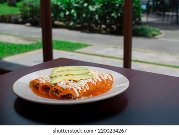 Mexican Regional Food Entomatadas With Chicken And Mexican Cheese Accompanied With Slices Of Avocado And Melted Cheese