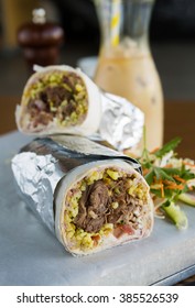 Mexican Shredded Beef Breakfast Burrito Sliced In Half Served With Ice Coffee.