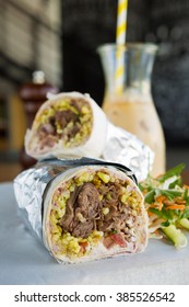 Mexican Shredded Beef Breakfast Burrito Sliced In Half Served With Ice Coffee.