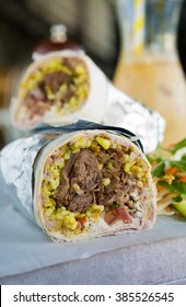 Mexican Shredded Beef Breakfast Burrito Sliced In Half Served With Ice Coffee.