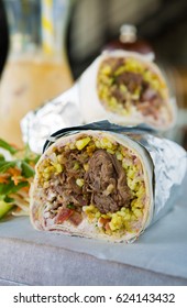 Mexican Shredded Beef Breakfast Burrito Sliced In Half Served With Ice Coffee.