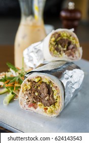 Mexican Shredded Beef Breakfast Burrito Sliced In Half Served With Ice Coffee.