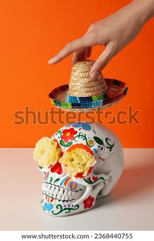 Mexican skull and sombrero in hand on orange background