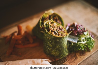 Mexican Spinach wrap. Vegetables green rolls served on wooden chopping board Healthy food