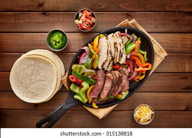 Mexican Steak And Chicken Fajitas In Cast Iron Skillet Shot Top Down With Corn Tortillas