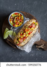 Mexican Street Style Hot Dog With Corn Salsa On A Wooden Cutting Board On Dark Background, Top View.