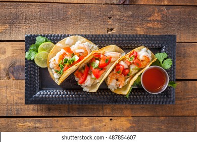 Mexican Street Tacos With Shrimp, Rice And Salsa In Yellow Corn Tortilla On Distressed Wood Table Selective Focus. Top View. - Powered by Shutterstock