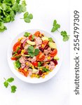 Mexican style salad with tuna, avocado, corn, beans, tomatoes and cilantro, white background, top view