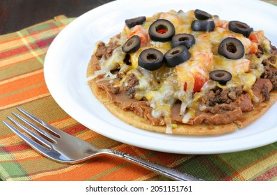 Mexican taco pizza with cheese, meat, tomatoes and refried beans.