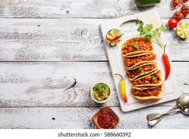 Mexican Tacos With Ground Beef, Beans And Salsa On Cutting Board Over Wooden Background. Top View