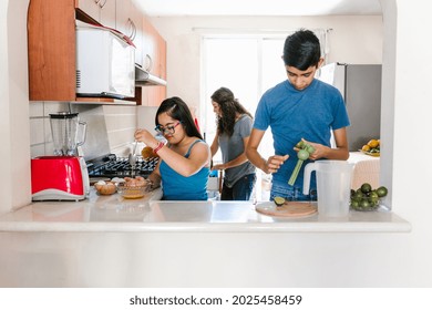 Mexican Teenage Girl With Down Syndrome With Her Family Cooking In The Kitchen At Home, In Disability Concept In Latin America