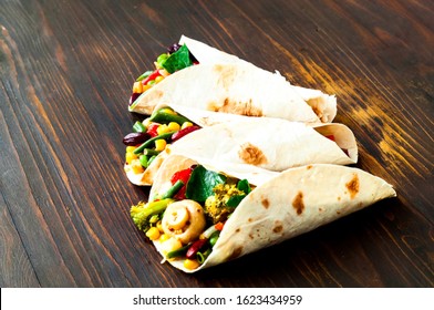 Mexican tortilla with vegetable and mushroom fillings on wooden background. Healthy eating concept. Budget-friendly menu.Close-up - Powered by Shutterstock