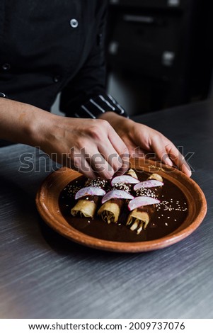 mexican woman cooking mole poblano enchiladas traditional food in a restaurant in Mexico