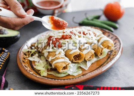 Mexican woman cooking tacos dorados called flautas with chicken, traditional fried food in Mexico Latin America
