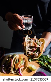 Mexican woman hands holding tacos and mezcal shot traditional food in Mexico city
