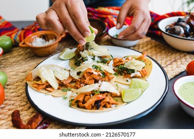 Mexican woman hands preparing tacos al pastor with sauce in Mexico city