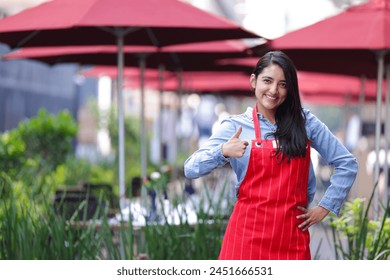 mexican woman restaurant owner smiling, looking at the camera and giving a thumbs up sign of ok - Powered by Shutterstock