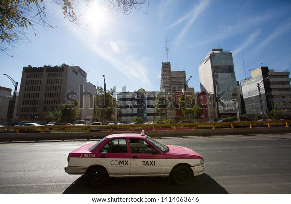Mexico\
City, Federal District /Mexico - December 27, 2018: An iconic Pink\
Mexico City Taxi drives down Avienda Chapultepec, in the\
neighborhood of Juárez in heart of Mexico\
City.