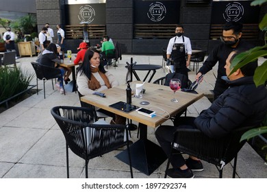 Mexico City, Mexico - January 18, 2021: A Waiter Serves Customers In A Restaurant Offering Outdoor Service To Follow COVID-19 Protocols.