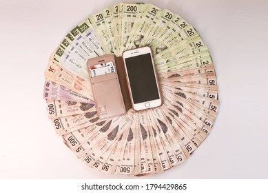 MEXICO CITY, MEXICO - Jul 12, 2020: An Overhead Shot Of Colorful Peso Banknotes Organized In A Circle With A Phone In The Middle