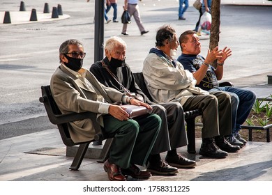 MEXICO CITY, MEXICO - JUNE 13, 2020: A Group Of Elderly Friends Enjoy The Evening In A Public Bench Wearing Prevention Masks In Quarantine Covid19.