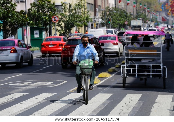 Mexico City, Mexico - September 20,\
2021: Cyclist ride he\'s bicycle along the bike path in a downtown\
street of CDMX amid the Coronavirus COVID-19\
pandemic.